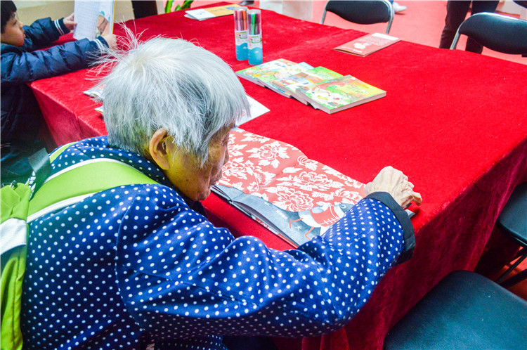 20171216 画展上,一名89岁的老奶奶对符文征老师的画册十分感兴趣 郑皓芳摄.JPG